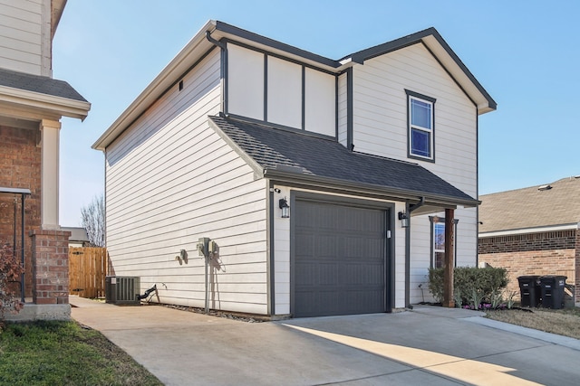 view of front of home featuring a garage, driveway, roof with shingles, and central air condition unit