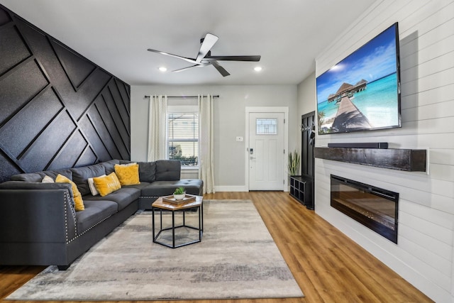 living room with ceiling fan, recessed lighting, a large fireplace, wood finished floors, and baseboards