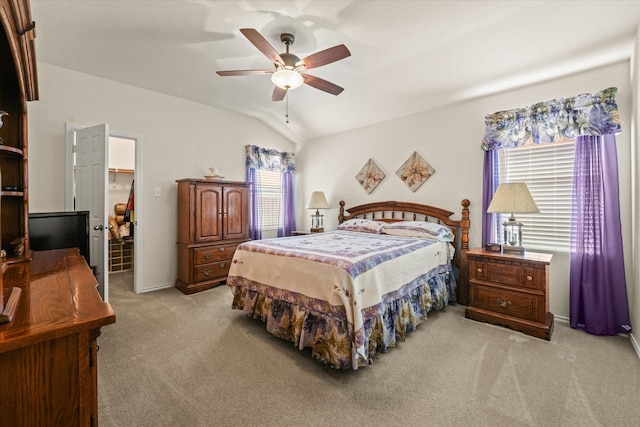 bedroom featuring a ceiling fan, light colored carpet, vaulted ceiling, and a spacious closet