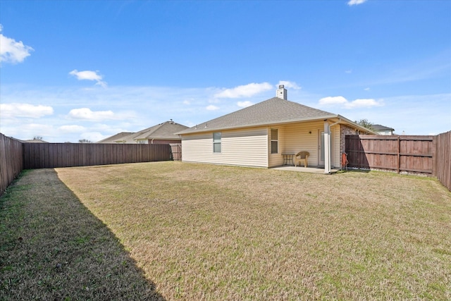 exterior space with a fenced backyard, brick siding, a yard, a chimney, and a patio area