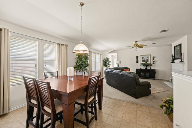 dining room with light tile patterned floors, visible vents, a ceiling fan, and light colored carpet