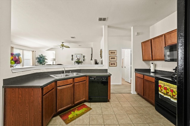 kitchen with black appliances, dark countertops, a sink, and visible vents