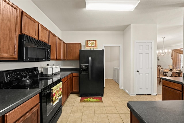 kitchen with dark countertops, black appliances, a chandelier, and washing machine and clothes dryer