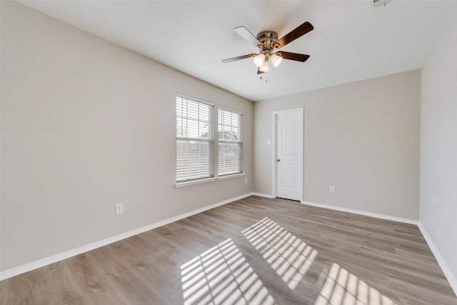 spare room featuring baseboards, ceiling fan, and light wood finished floors