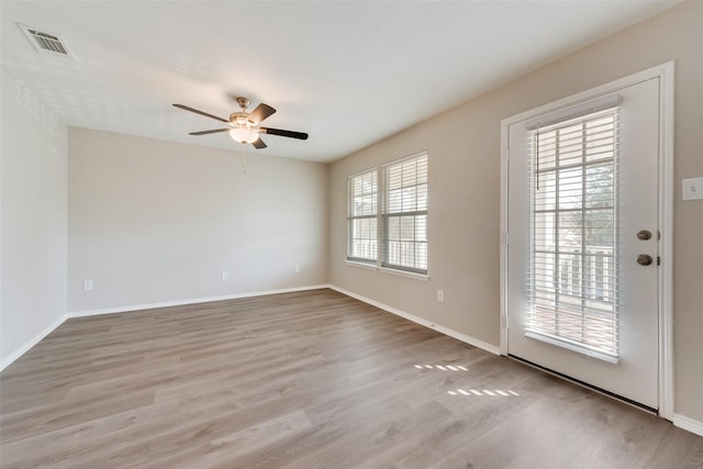 spare room featuring a ceiling fan, wood finished floors, visible vents, and baseboards