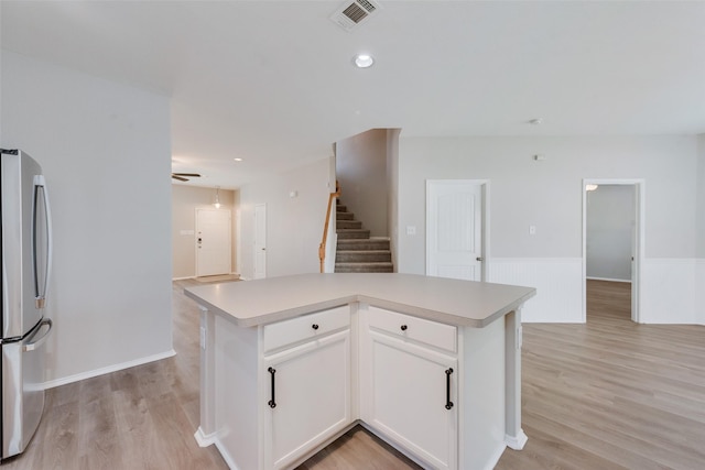 kitchen with visible vents, light wood-style flooring, freestanding refrigerator, and white cabinets