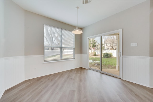 empty room featuring a wainscoted wall, visible vents, and wood finished floors