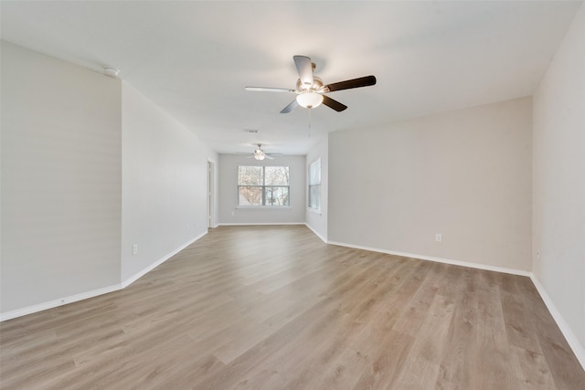 empty room with light wood-style floors, visible vents, baseboards, and a ceiling fan