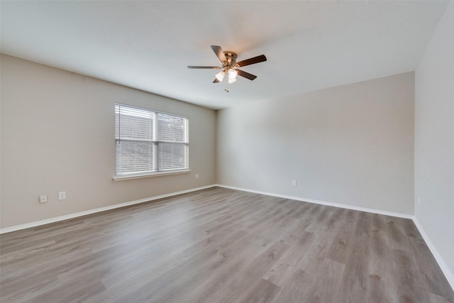 spare room with light wood finished floors, baseboards, and a ceiling fan