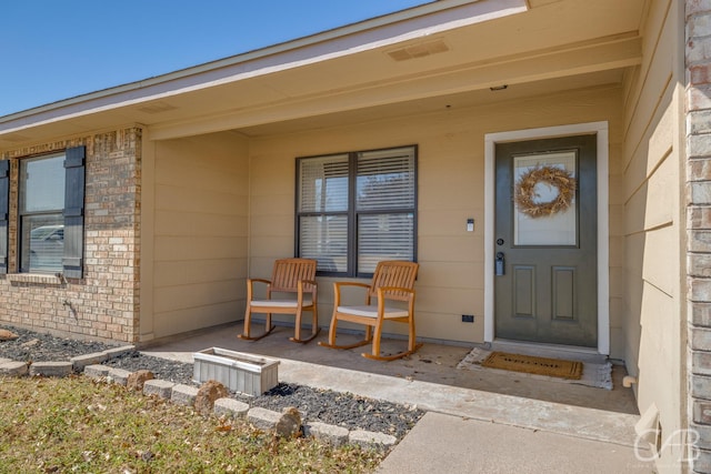 property entrance with a porch and brick siding