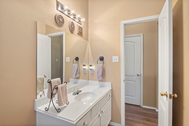 bathroom with baseboards, wood finished floors, and vanity