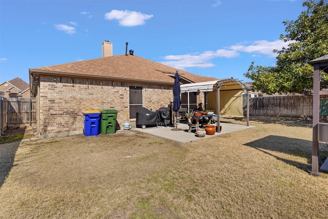 back of property with a chimney, a patio area, brick siding, and a fenced backyard