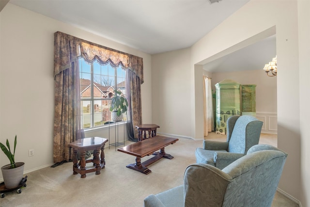 living area with a chandelier, a decorative wall, and carpet flooring