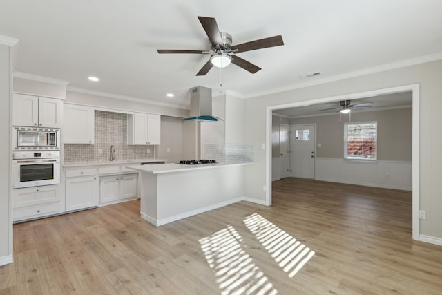 kitchen with visible vents, white cabinets, light countertops, appliances with stainless steel finishes, and wall chimney exhaust hood