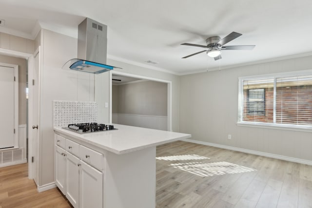 kitchen with light wood-style flooring, white cabinetry, ornamental molding, island exhaust hood, and stainless steel gas stovetop