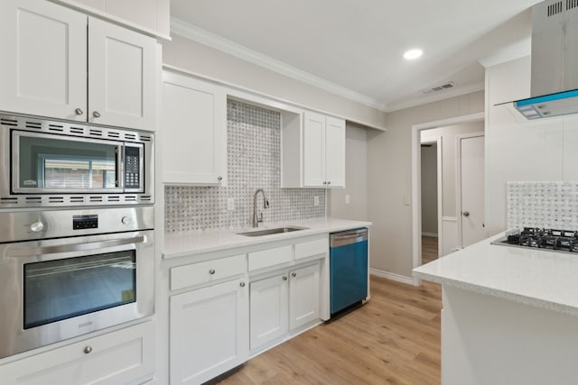 kitchen featuring wall chimney range hood, crown molding, stainless steel appliances, and a sink