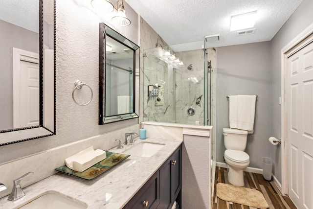 full bathroom featuring toilet, a marble finish shower, a sink, and wood finished floors