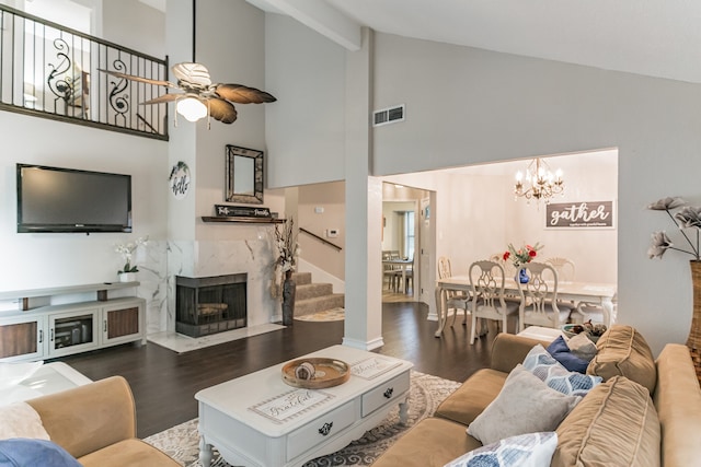 living area with visible vents, a premium fireplace, stairway, wood finished floors, and ceiling fan with notable chandelier