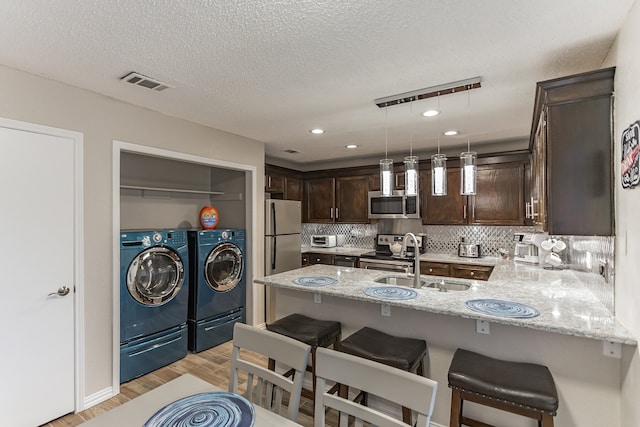 kitchen with visible vents, appliances with stainless steel finishes, a sink, dark brown cabinetry, and independent washer and dryer