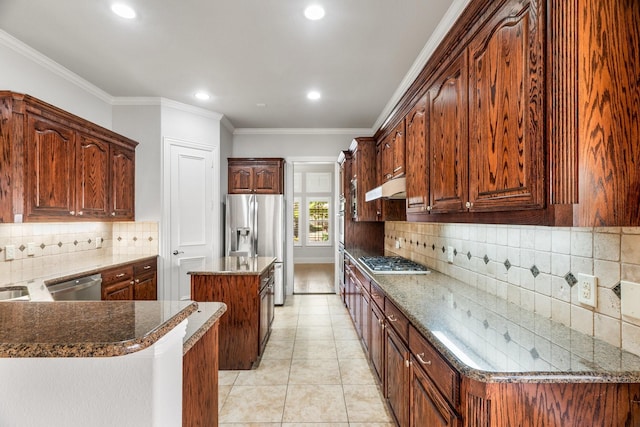 kitchen with appliances with stainless steel finishes, a center island, crown molding, under cabinet range hood, and light tile patterned flooring