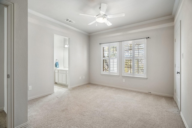 unfurnished bedroom featuring crown molding, light colored carpet, visible vents, connected bathroom, and baseboards