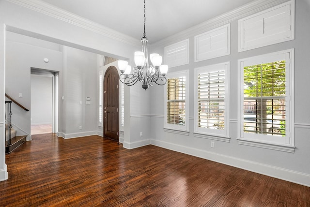 unfurnished dining area with wood finished floors, baseboards, stairs, ornamental molding, and an inviting chandelier