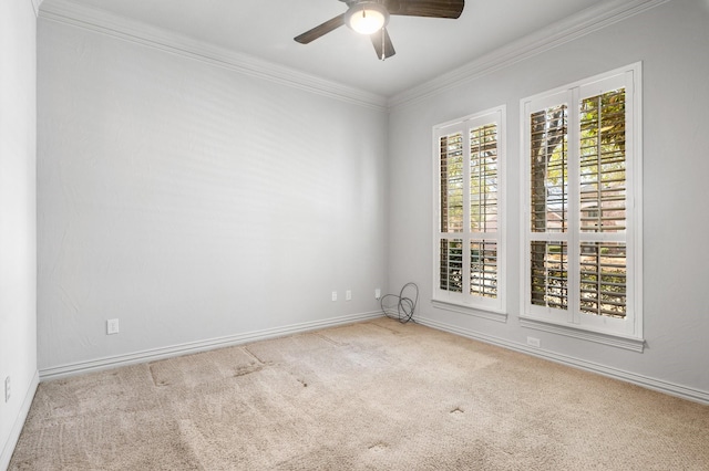 carpeted spare room featuring crown molding, baseboards, and ceiling fan