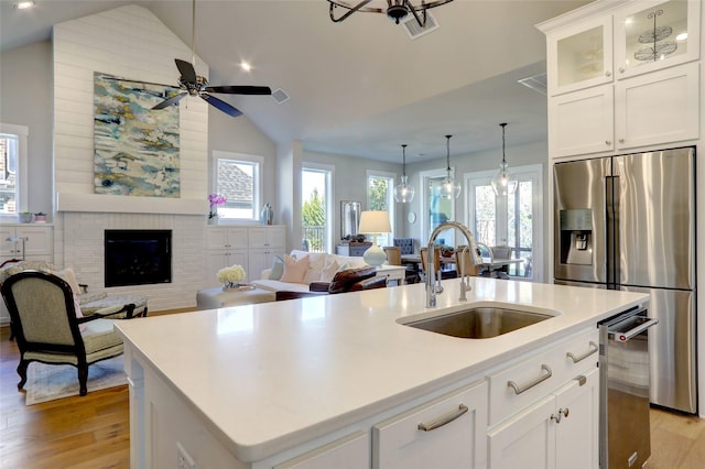 kitchen featuring a brick fireplace, stainless steel appliances, a sink, and open floor plan