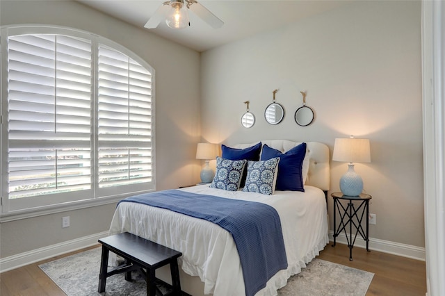 bedroom with a ceiling fan, baseboards, and wood finished floors