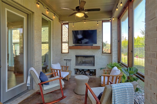 sunroom with a large fireplace and ceiling fan