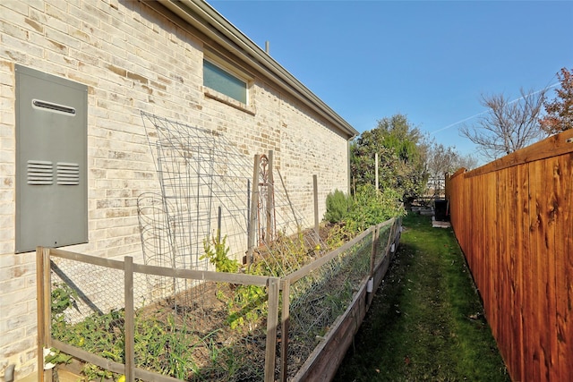 view of side of property with brick siding, a vegetable garden, and fence