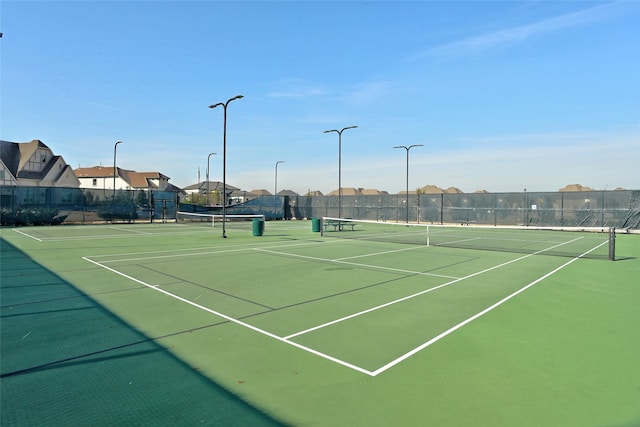 view of tennis court with community basketball court and fence