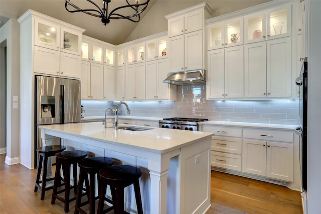 kitchen with stainless steel fridge with ice dispenser, stove, light countertops, under cabinet range hood, and a sink