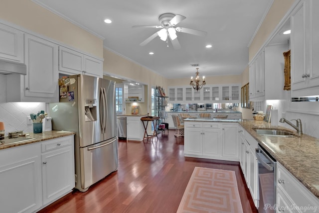 kitchen featuring stainless steel appliances, a peninsula, dark wood-style flooring, a sink, and white cabinets