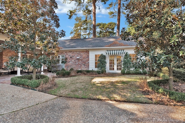 view of front of home with french doors, a front lawn, and brick siding