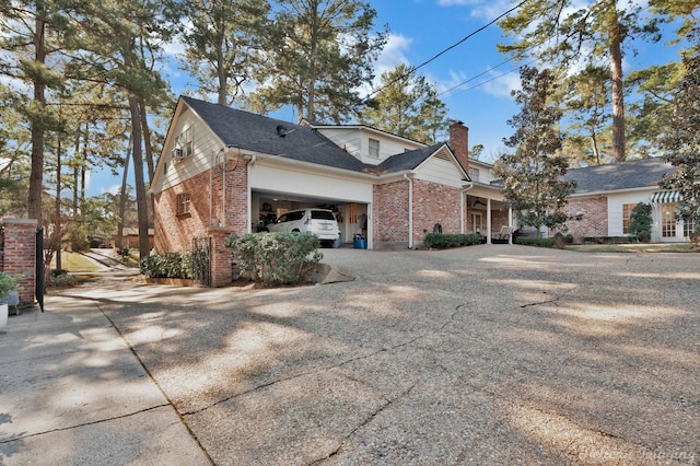 view of home's exterior with a garage, brick siding, a shingled roof, driveway, and a chimney