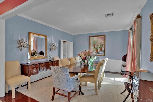 dining space with wainscoting, visible vents, and crown molding