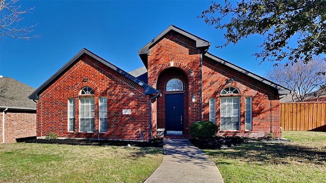 view of front facade featuring a front yard, fence, and brick siding