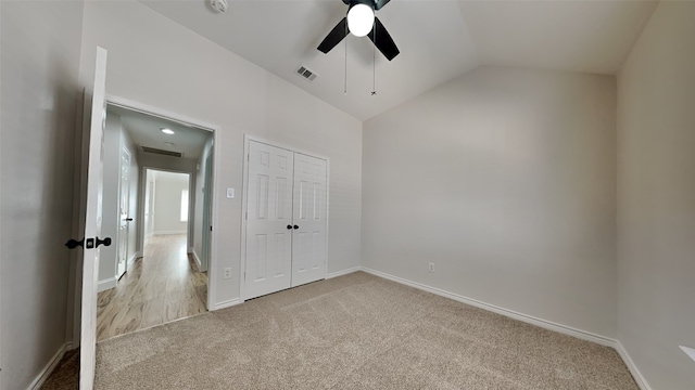 unfurnished bedroom with lofted ceiling, a closet, visible vents, light carpet, and baseboards