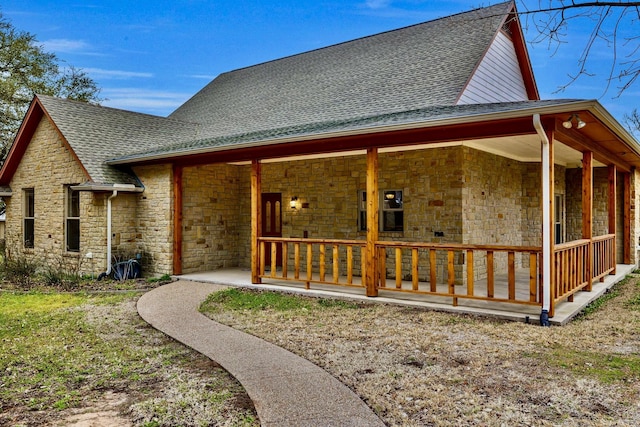 back of house with stone siding and a shingled roof