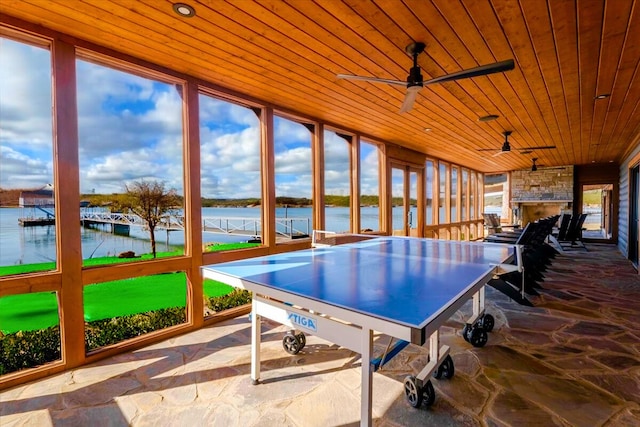 game room featuring a water view, wooden ceiling, stone floors, and a ceiling fan