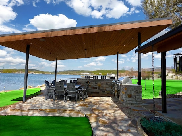 view of patio featuring a water view, a grill, an outdoor kitchen, and outdoor dining space