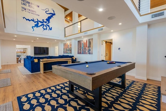 playroom with baseboards, visible vents, a high ceiling, and wood finished floors