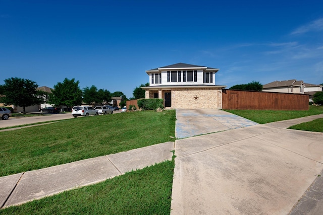 view of front facade featuring brick siding, a front yard, and fence