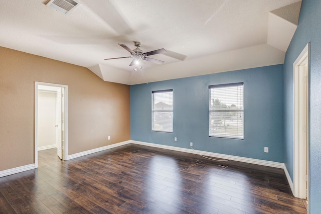 spare room with dark wood-style floors, lofted ceiling, visible vents, and a ceiling fan