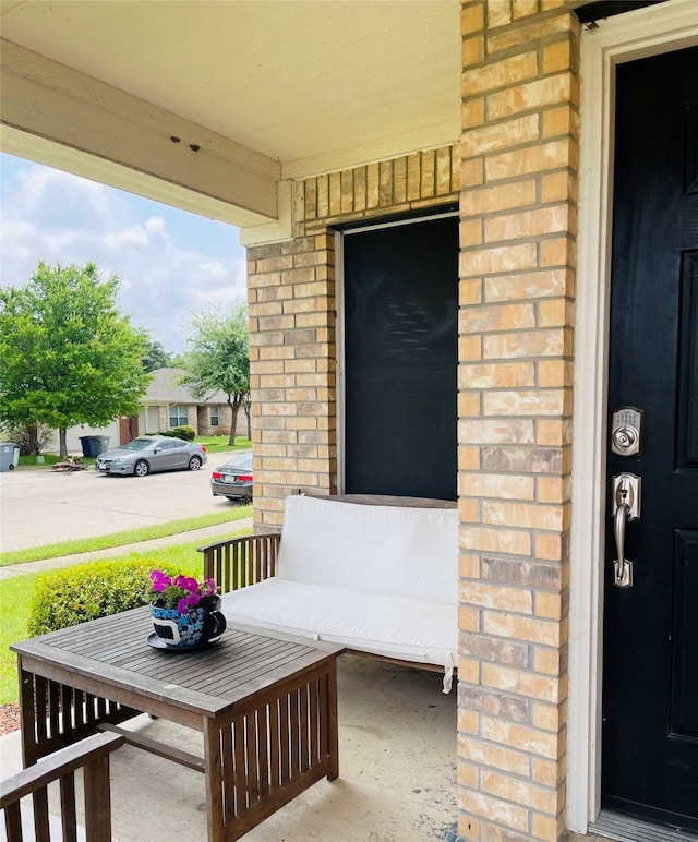 view of exterior entry featuring a porch and brick siding