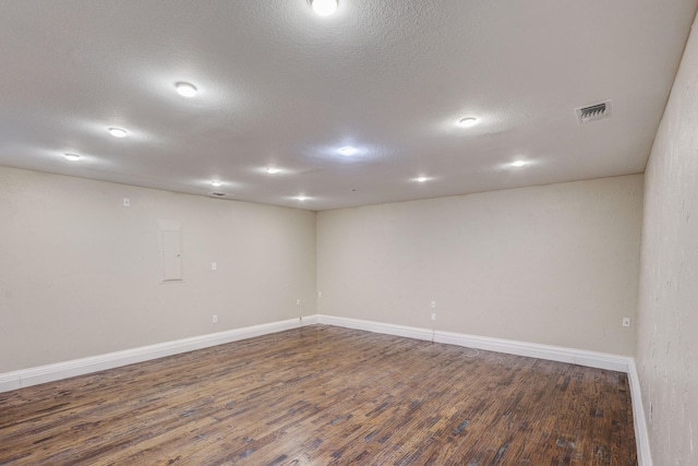 spare room with electric panel, baseboards, visible vents, dark wood finished floors, and a textured ceiling