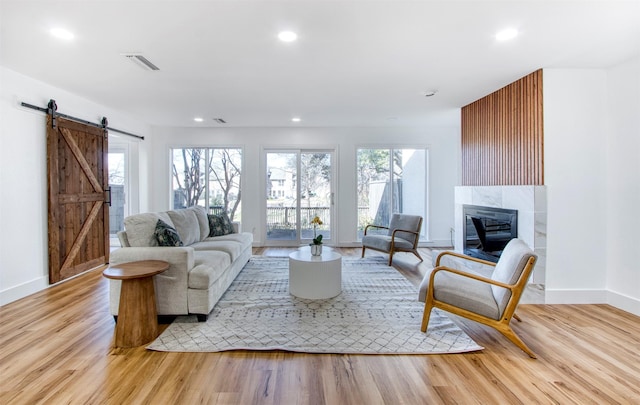 living room with a healthy amount of sunlight, wood finished floors, visible vents, and a barn door