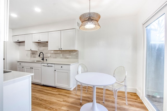 kitchen featuring light countertops, backsplash, light wood-style floors, a sink, and dishwasher