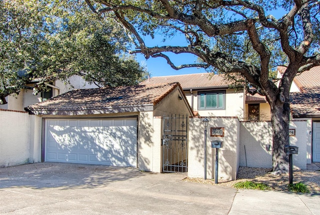 view of front facade with driveway, a garage, a tile roof, a gate, and stucco siding